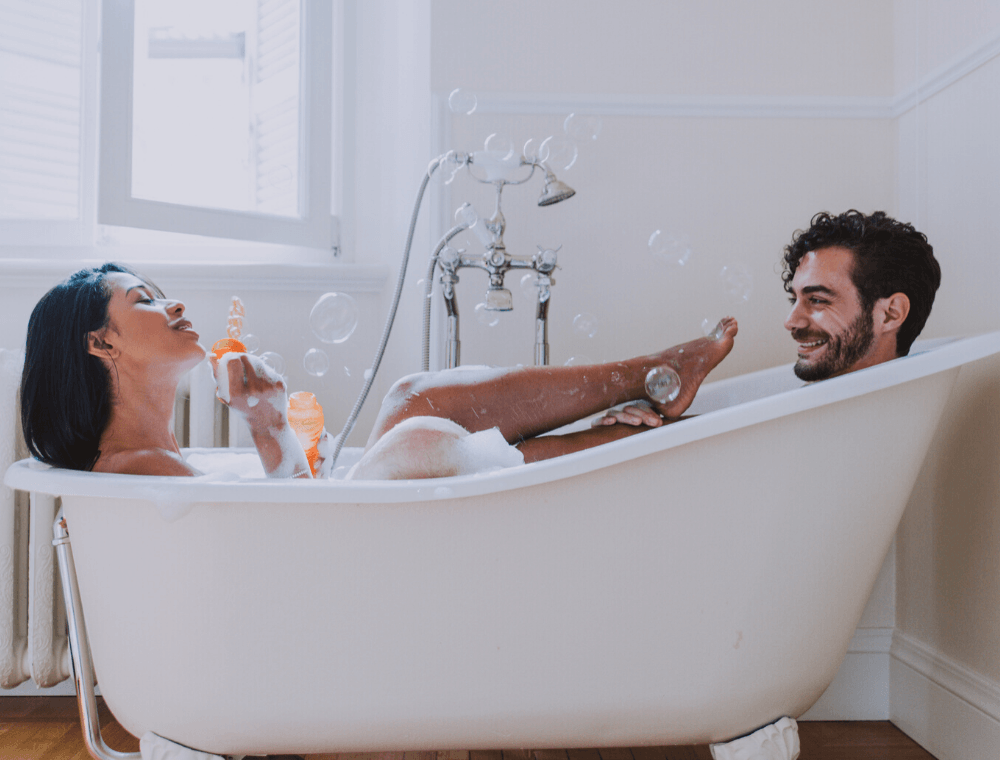 Couple taking bath together blowing bubbles
