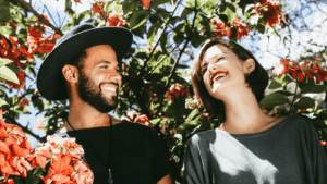 Couple laughing together with background of trees and flowers